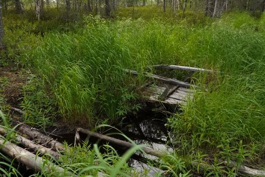 A wooden bridge across a stream in the woods. Overcoming a small river.