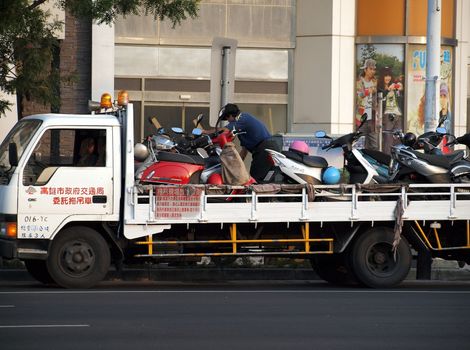 KAOHSIUNG, TAIWAN - DECEMBER 28: Police enforce new traffic rules and tow away illegally parked scooters on December 28, 2011 in Kaohsiung