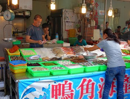 KAOHSIUNG, TAIWAN -- OCTOBER 11, 2014: A customer chooses fresh fish to have it prepared by a seafood restaurant on the island of Cijin.