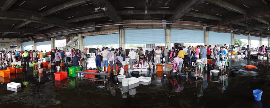 KAOHSIUNG, TAIWAN -- APRIL 24, 2016: Shoppers at the Sinda Port fish market check out the fish and seafood that is on sale in baskets and crates.