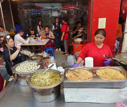KAOHSIUNG, TAIWAN -- FEBRUARY 6, 2019: A street vendor cooks fried noodles, fish balls and pickled bamboo soup.

