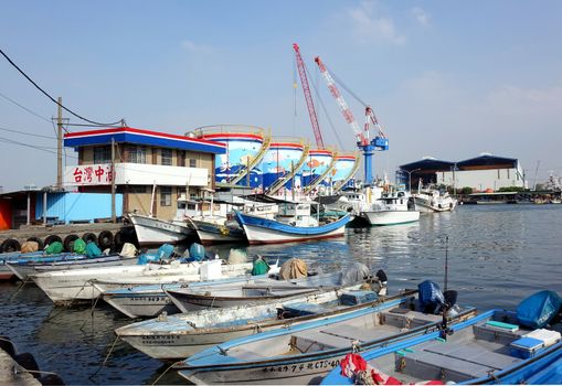 KAOHSIUNG, TAIWAN -- OCTOBER 11, 2014: A harbor for small fishing boats with storage tanks in the background on the island of Cijin.