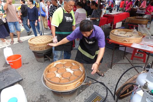 KAOHSIUNG, TAIWAN -- DECEMBER 1, 2019: A street vendor cooks steamed rice cakes sprinkled with brown rice powder.
