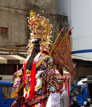 KAOHSIUNG, TAIWAN -- MARCH 16, 2014: A large statue on stilts representing a popular deity is paraded through the streets as part of a religious ceremony.