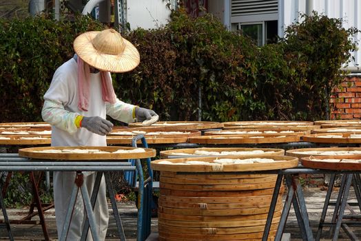 TAINAN, TAIWAN -- MARCH 4, 2014: An unidentified worker checks on noodles that are dried in the sun before packaging, a local specialty in southwest Taiwan.