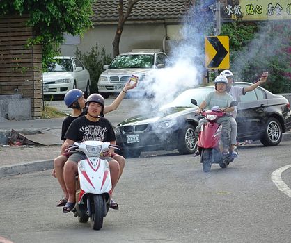 KAOHSIUNG, TAIWAN -- MARCH 29, 2014: Campain workers on scooters use firecrackers to announce the arrival of an election candidate in the run up to the 2014 local elections.