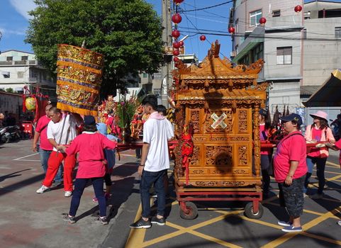 KAOHSIUNG, TAIWAN -- JUNE 10 , 2017: Religious devotees push a palanquin with intricate wood carvings during a religious ceremony.