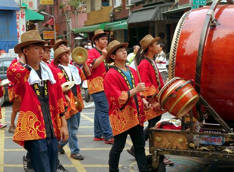 KAOHSIUNG, TAIWAN -- APRIL 20, 2014: Young men in indentical hats and robes play percussion instruments in a religious procession.