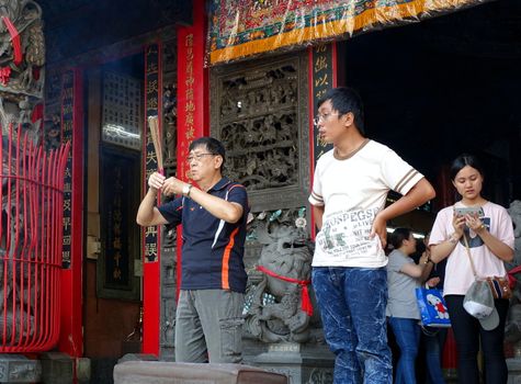 KAOHSIUNG, TAIWAN -- OCTOBER 15, 2016: An unidentified man burns incense and says prayers at the Yuan Di Temple in Kaohsiung City.