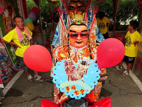 KAOHSIUNG, TAIWAN -- AUGUST 15, 2015: A masked dancer in a modernized costume of the Chinese Third Prince tradition poses on a quad bike at a local temple carnival.