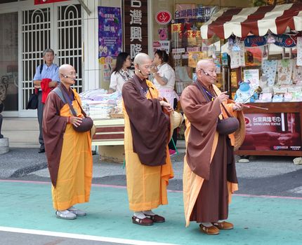 KAOHSIUNG, TAIWAN -- OCTOBER 15, 2016: Three Buddhist monks prepare to chant scriptures during the yearly Wannian Folk Festival.
