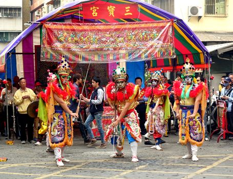 KAOHSIUNG, TAIWAN -- MARCH 16, 2014: Three young men with painted facial masks and dressed up as ancient warriors pose at a local temple ceremony.