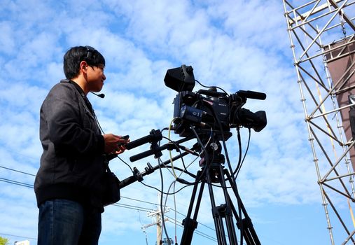 LUJHU, TAIWAN -- DECEMBER 12, 2015: A professional camera man films the stage performances at the Lujhu Tomato Festival.
