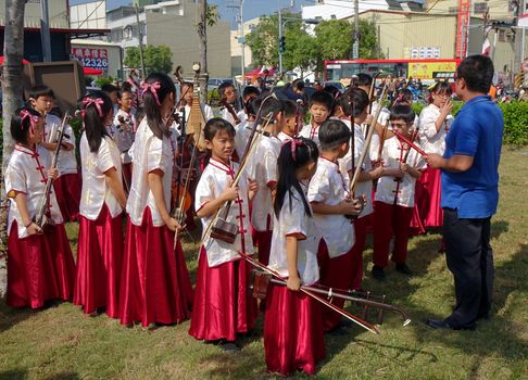 LUJHU, TAIWAN -- DECEMBER 12, 2015: A children's orchestra for traditional Chinese music waits for their performance at the 2015 Lujhu Tomato Festival.