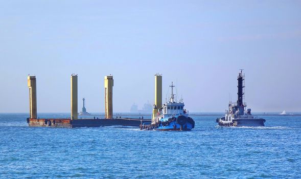 KAOHSIUNG, TAIWAN -- DECEMBER 22, 2018: A tugboat pulls a large floating steel construction element into the port of Kaohsiung.
