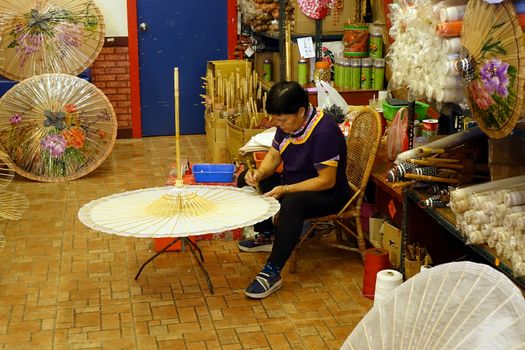 KAOHSIUNG, TAIWAN -- JULY 24, 2016: A female craftsperson makes oil-paper umbrellas, which is a traditional art and craft product by the Chinese Hakka people.