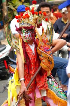 KAOHSIUNG, TAIWAN -- MARCH 16, 2014: A young man with painted facial mask and dressed up as an ancient warrior poses at a local temple ceremony.