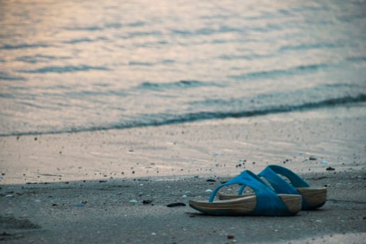 One pair of slippers Placed on the beach Giving a lonely mood.