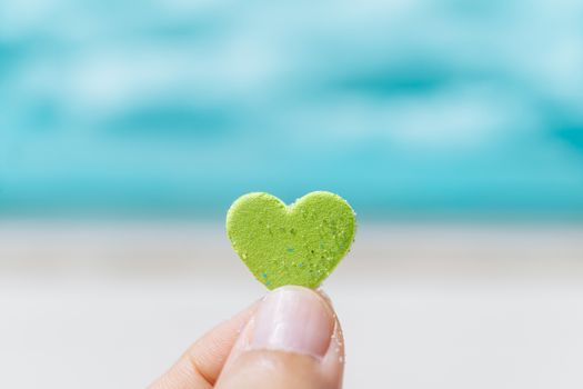 Hand hold little heart meaning feel love with summer beach with blue sky background.