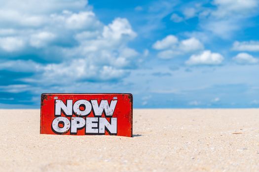 Now open sign board stand on sand summer beach background metaphor to time to travel relax tourism season with copyspace background.