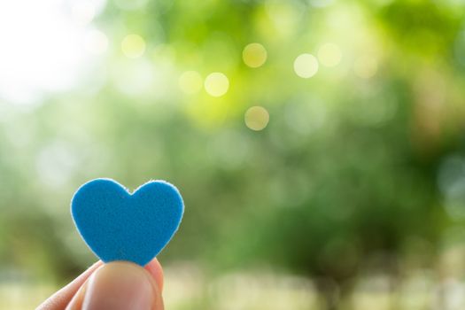 Hand hold little heart meaning feel love with green nature bokeh background.