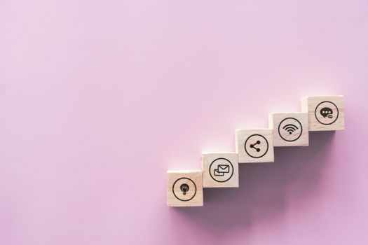 Close up of wood block stacking as step stair on paper pink pastel background with copy space. Business online icons concept.