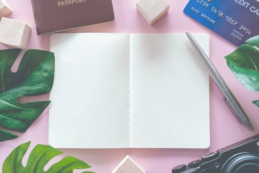 Top view of blank space white notebook and pen with travel gear such as passport, camera, credit card and  wall as frame of picture background. 