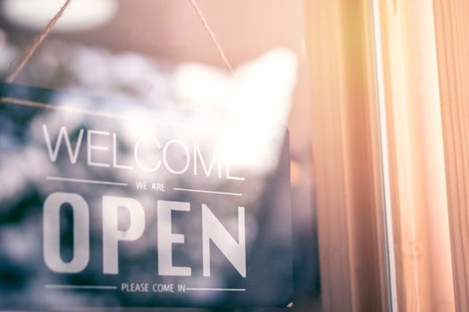 Open sign vintage style at coffee cafe shop with sunrise and bokeh. Metaphor of start or begin a own business. 