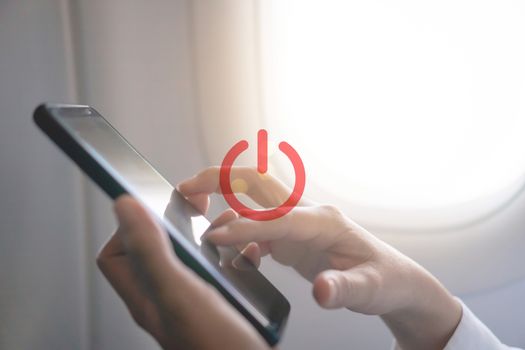 Woman hand use smartphone in airplane with turn off or switch off sign icon during flight.Work and travel concept.