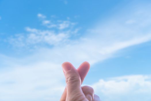 Love symbol of korean with your fingers. A female hand depicts a heart in front of beautiful nature. 