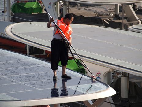 KAOHSIUNG, TAIWAN - FEBRUARY 22: An unidentified crew member washes the solar panelled roof of a sightseeing boat on the Love River on February 22, 2013 in Kaohsiung.