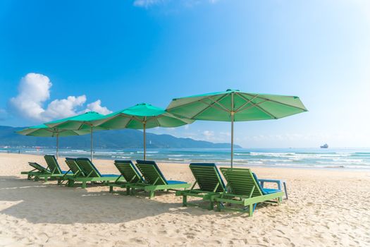 Beach chairs with outdoor umbella at summer beach with blue sky.