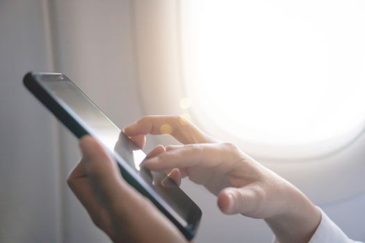 Woman hand use smartphone in airplane in offline mode during flight work and travel concept.