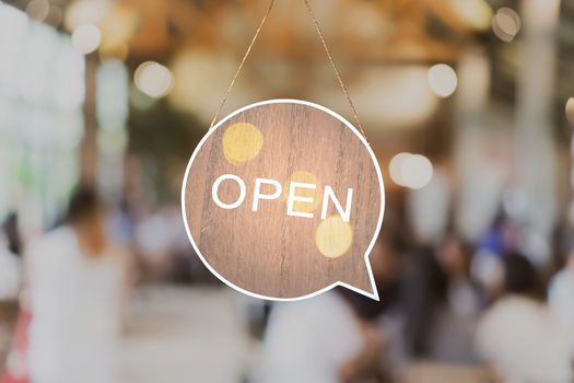 A business sign that says Open hang on cafe glass door or restaurant at entrance. Vintage color tone style.