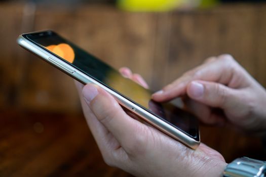 Woman hand using smartphone in cafe shop background. Business, financial, trade stock maket and social network concept.