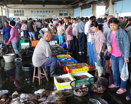 KAOHSIUNG, TAIWAN -- SEPTEMBER 6, 2015: Shoppers at the Sinda Port fish market check out the fish and seafood that is on sale in baskets and crates.