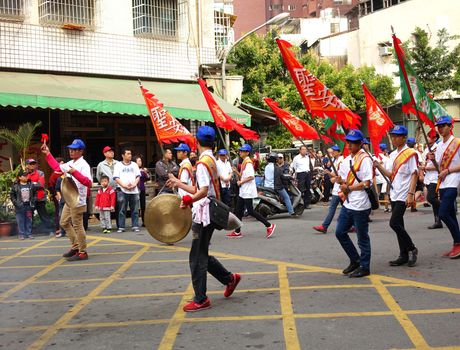 KAOHSIUNG, TAIWAN -- MARCH 16, 2014: Religious devotees carry flags and beat gongs in a procession that is part of a local religious ceremony.