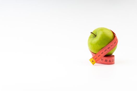 Green apple with red measuring tape. Health care and body fitness concept