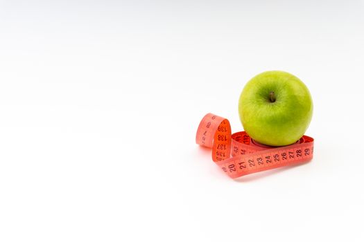 Green apple with red measuring tape. Health care and body fitness concept