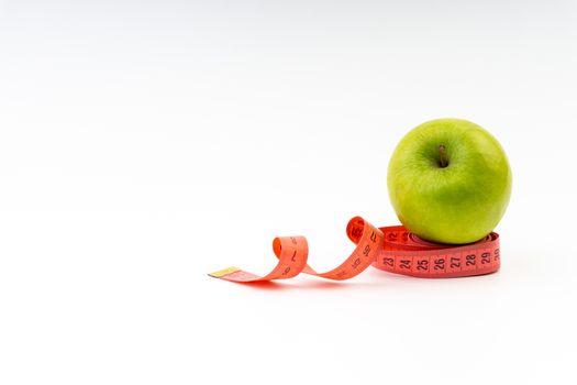 Green apple with red measuring tape. Health care and body fitness concept