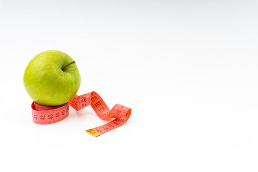 Green apple with red measuring tape. Health care and body fitness concept