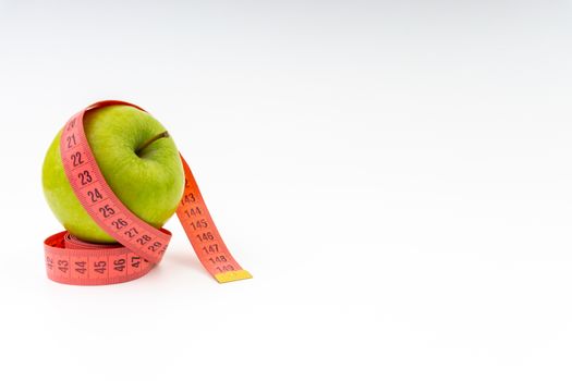 Green apple with red measuring tape. Health care and body fitness concept