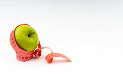 Green apple with red measuring tape. Health care and body fitness concept