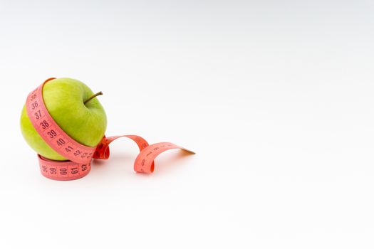 Green apple with red measuring tape. Health care and body fitness concept