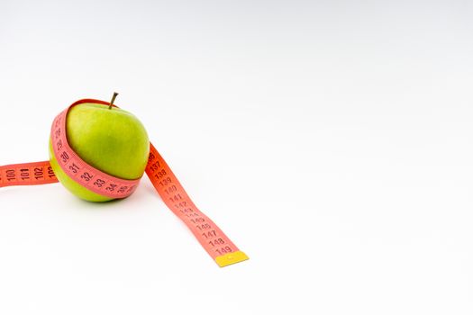 Green apple with red measuring tape. Health care and body fitness concept