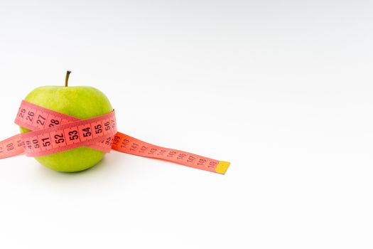 Green apple with red measuring tape. Health care and body fitness concept