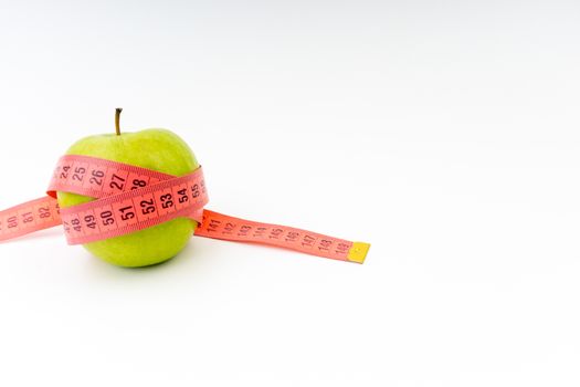 Green apple with red measuring tape. Health care and body fitness concept