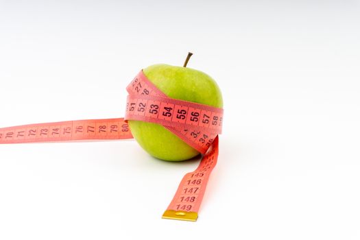 Green apple with red measuring tape. Health care and body fitness concept