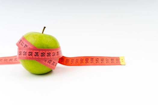 Green apple with red measuring tape. Health care and body fitness concept