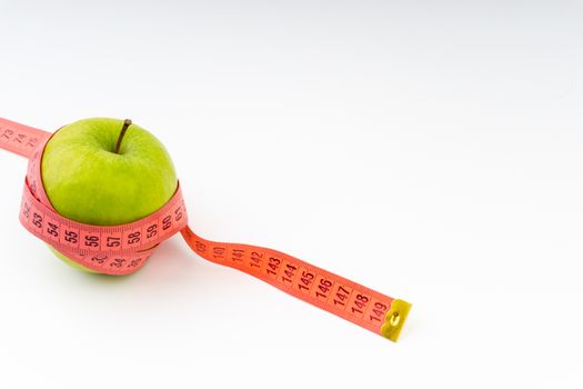 Green apple with red measuring tape. Health care and body fitness concept